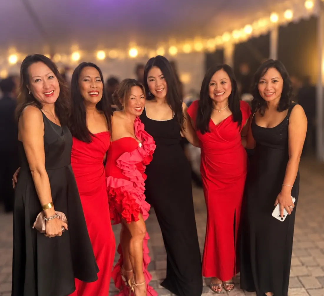 Six APWS members in black and red gowns under string lights
