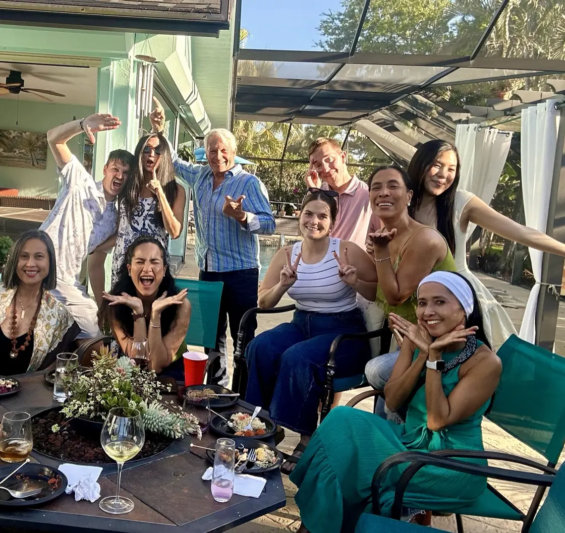 Members and guests laughing around a patio table